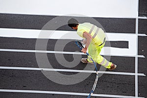 Road painter worker painting lines of a zebra crossing using paint sprayer gun