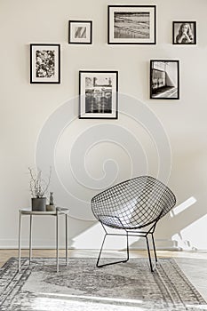 Gallery of black and white photos on empty wall of spacious living room interior