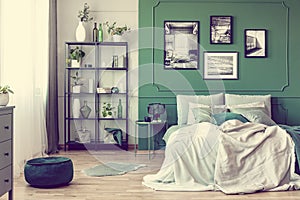 Gallery of black and white poster on green wall behind king size bed with pillows and blanket