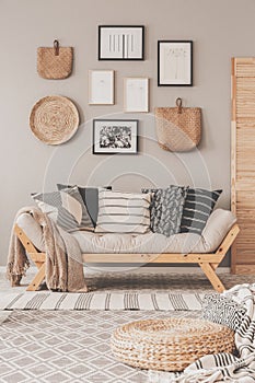 Gallery of black and white posters and wicker accessories on beige wall of Scandinavian living room photo