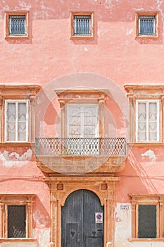 Gallipoli, Apulia - A pink facade with a barn door and several w