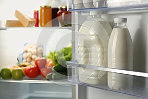 Gallon and bottle of milk in refrigerator, closeup. Space for text