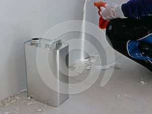 A gallon of thinner placed next to old concrete wall, while a painter is removing sticky rough glue and tape remain on the wall, photo