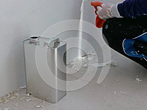 A gallon of thinner placed next to old concrete wall, while a painter is removing sticky rough glue and tape remain on the wall,