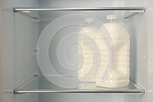 Gallons of fresh milk in refrigerator, closeup. Space for text