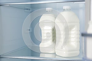 Gallons of fresh milk in refrigerator, closeup. Space for text