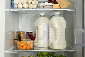 Gallons of milk and different products in refrigerator, closeup