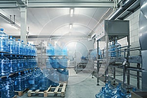 Gallons or plastic bottles of purified drinking water on pallets in water production factory interior inside