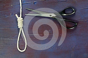 Gallows of white rope with scissors insinuating the cut of the rope