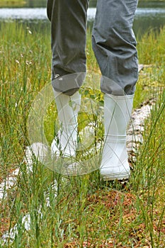 Galoshes, woman going in rubber boots in a meadow