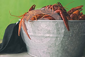 Galvanized steel bucket filled with boiled crawfish. Side view on wood table with copy space.