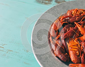 Galvanized steel platter filled with boiled crawfish. Close view, turquoise wood table with copy space.