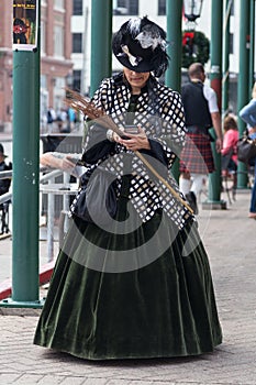 Galveston, TX/USA - 12 06 2014: Lady dressed in Victorian style texting on the phone at Dickens on the Strand Festival in Galvesto