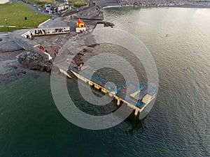 Galway, Ireland - 04.30.2021: Sun rise over Galway city, People swimming in the ocean by Blackrock public diving board. Calm