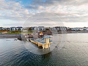 Galway, Ireland - 04.30.2021: Sun rise over Galway city, People swimming in the ocean by Blackrock public diving board. Calm