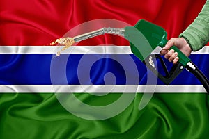 GAMBIA flag Close-up shot on waving background texture with Fuel pump nozzle in hand. The concept of design solutions. 3d