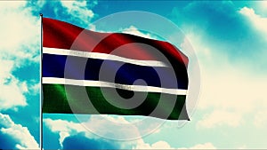 Gambia flag waving in the wind on a flagpole, seamless loop. Motion. Gambian highly detailed fabric texture on a blue