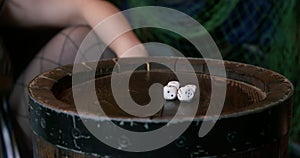 Gambler or sharper shakes a cup with dice and abruptly lays them out on wooden table, close up. Opponent checks dropped