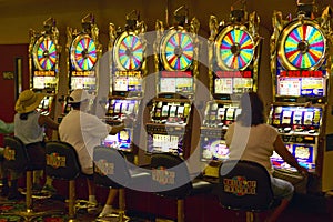 Gamblers putting coins into slot machines in Las Vegas, NV