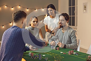 Group of young friends awaiting for card from deck during betting and playing poker