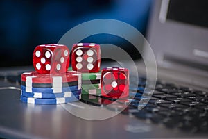 Gambling chips and red dice on laptop keyboard background