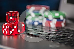 Gambling chips and red dice on laptop keyboard background