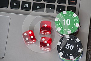 Gambling chips and red dice on laptop keyboard background