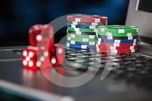 Gambling chips and red dice on laptop keyboard background