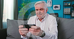 Gambling elderly senior 60s years old using play mobile cell phone hold gadget smartphone video