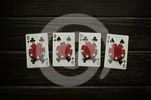 Gambling game of poker with a successful winning combination of two pairs. Playing cards and chips on a black vintage table in a