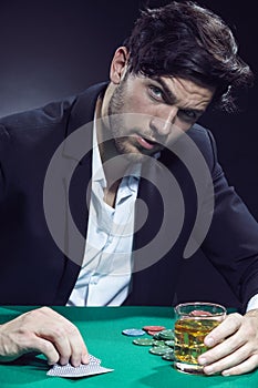 Gambling Ideas. One Concentrated Thoughful Handsome Caucasian Brunet Cards Player At Pocker Table With Chips and Cards While