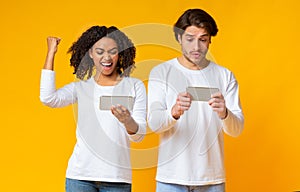Gambling interracial couple with smartphones competing in video games