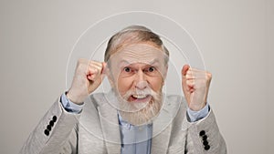 Gambling man raising hands in studio. Excited old guy showing emotions indoors.