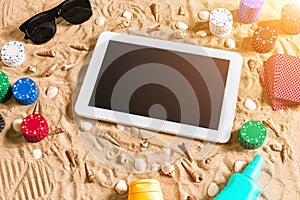 Gambling on vacation concept - white sand with seashells , colored poker chips and cards. Top view