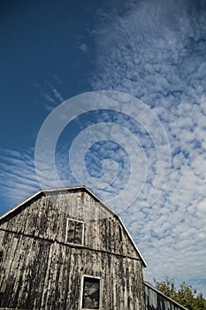 Gambrel roof black weathered barn with deep blue sky and cloudscapes