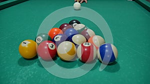 game of billiards with colored and numbered balls. 8 ball. green table and moving balls with billiard cue. panning the