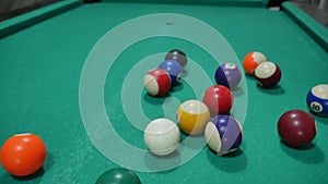 game of billiards with colored and numbered balls. 8 ball. green table and moving balls with billiard cue. panning the