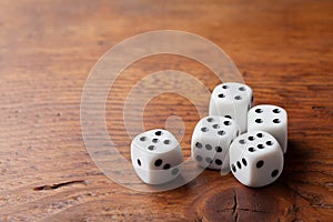 Game of chance concept. Gambling devices. White dice on rustic wooden board. Copy space for text.