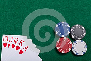 Game chips and cards on the green poker table. A winning combination in Royal Flush poker