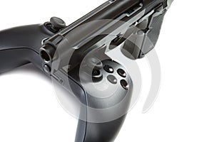 Game controller and handgun near it - studio close up shot. Virtual and real life concept