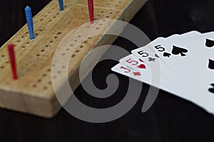 Playing cards and cribbage board on black background