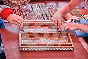 The game of two people in the old backgammon. Hands players move chips on the backgammon. Vintage middle Eastern style furnishings
