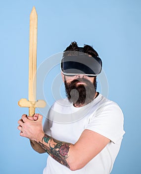 Gamer concept. Hipster on serious face enjoy play game in virtual reality. Guy with head mounted display holds sword