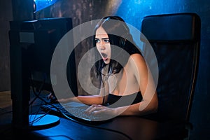 Gamer girl. Excited angry shocked young woman playing video games on a PC computer screaming looking on a screen