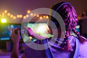 Gamer girl with a joystick plays on a console or computer using a gamepad, controller, joystick. Against the background of three