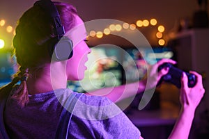 Gamer girl with a joystick plays on a console or computer using a gamepad, controller, joystick. Against the background of three