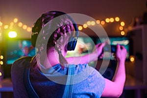 Gamer girl with a joystick plays on a console or computer using a gamepad, controller, joystick. Against the background of three