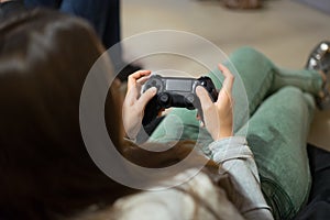 Gamer girl playing video games with joystick sitting on Bean bag chair