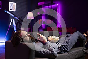 Man in home theatre playing videogames with bowl of popcorn in lap photo