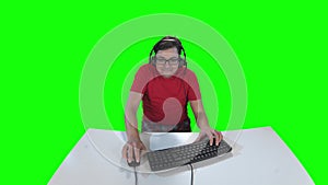Gamer playing computer game sitting at the table. Green screen